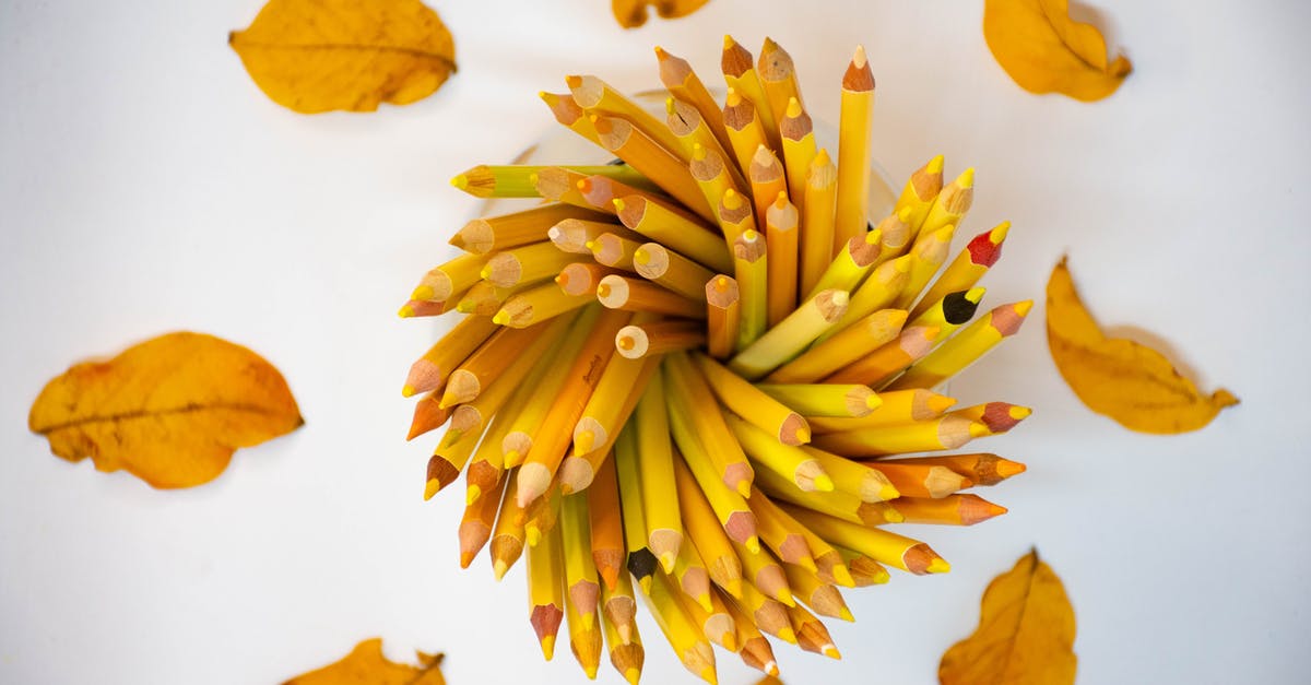 Hiking/nature around Lyon - Top view composition of yellow dry tree leaves arranged around holder with bright yellow pencils on white table Hiking/nature around Lyon - Top view composition of yellow dry tree leaves arranged around holder with bright yellow pencils on white table