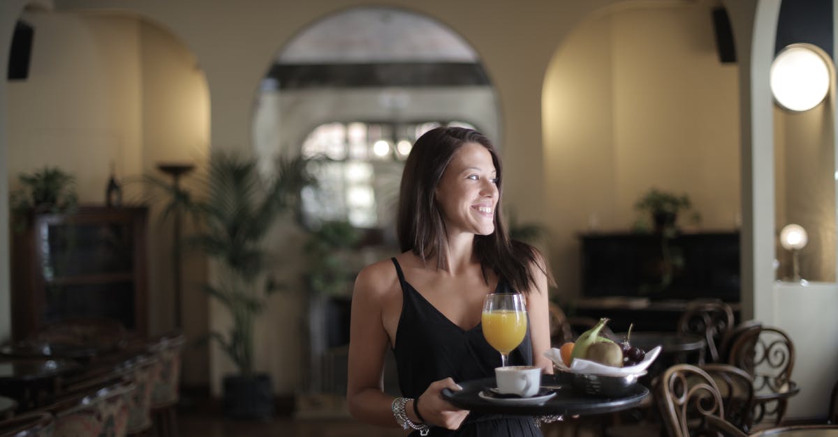 Hotel early arrival for another guest - Happy woman carrying tray with breakfast in hotel restaurant Hotel early arrival for another guest - Happy woman carrying tray with breakfast in hotel restaurant