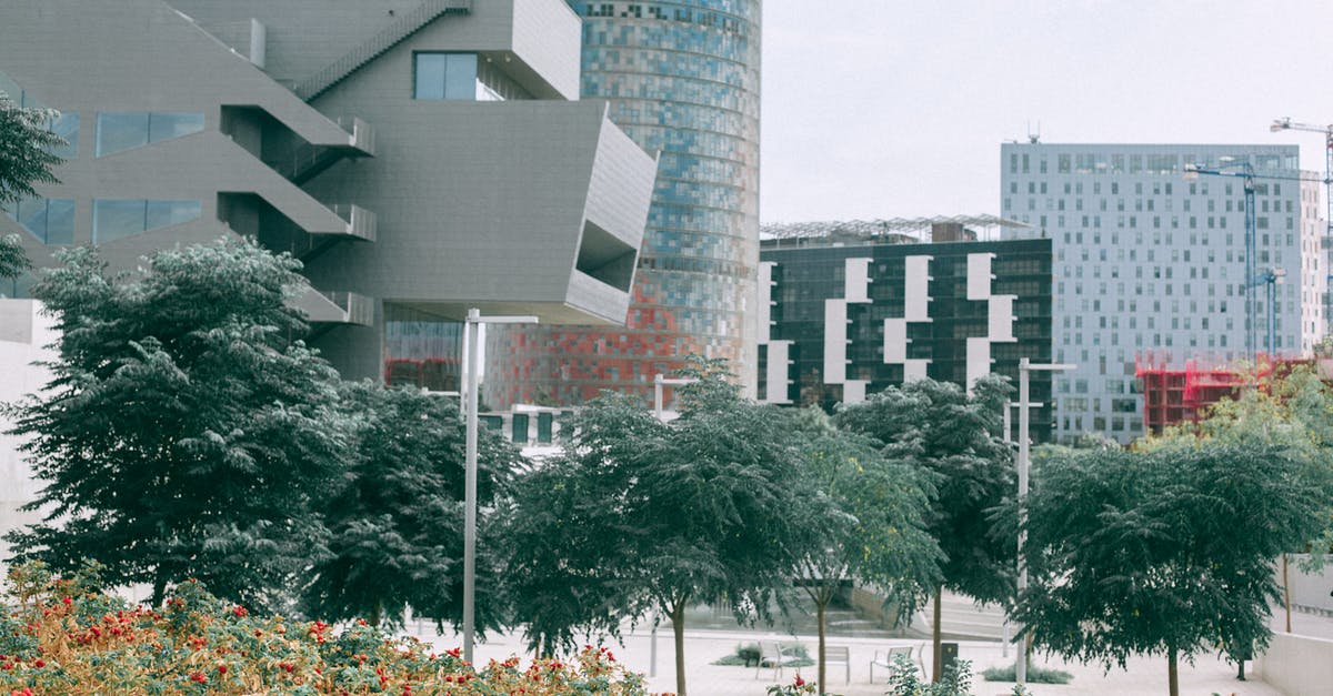 How are border closures enforced in the Schengen area given the large number of crossing points? - Lush plants and green trees against complex of big modern geometric buildings futuristic architecture style