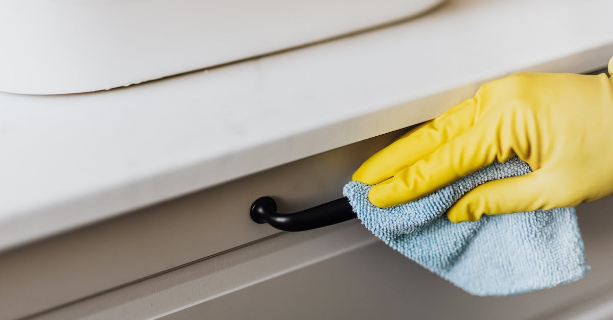 How are customs duties handled by the Fedex "Baggage Free" service? - From above of crop faceless person in yellow gloves cleaning handle of cabinet with microfiber cloth in modern bright bathroom
