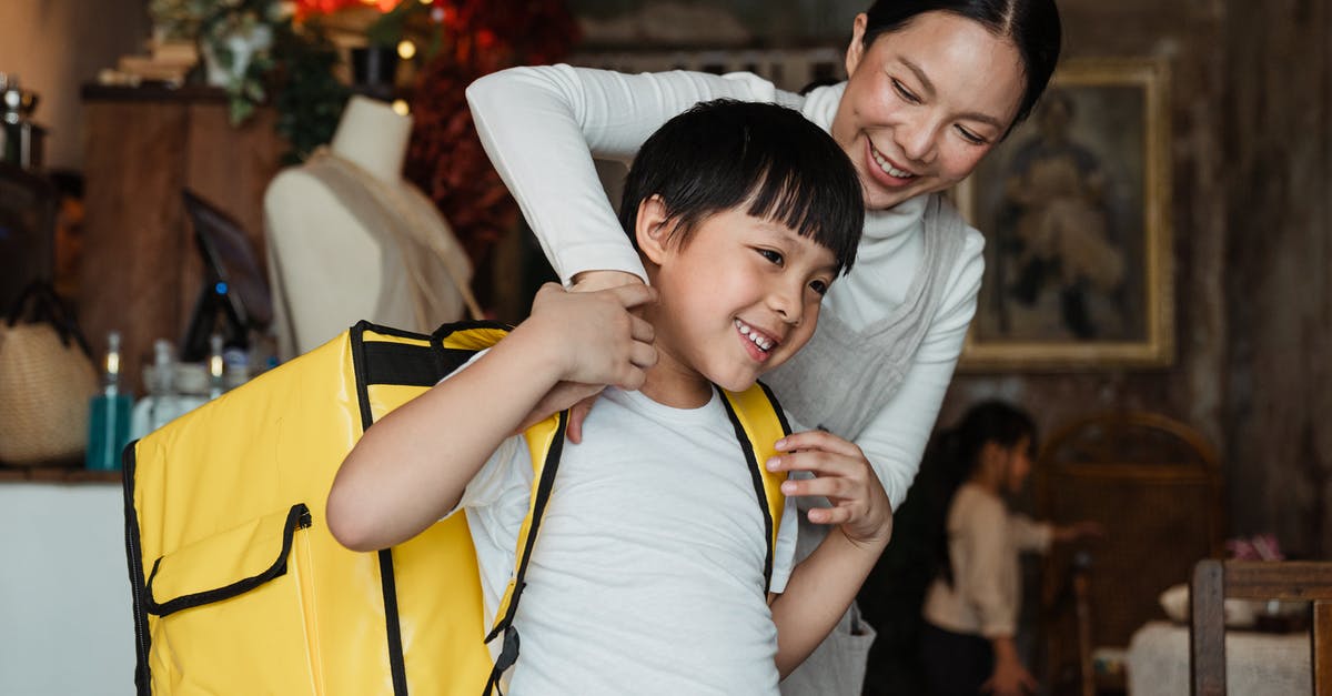 How big of a backpack should I buy? (Trans-Mongolian) - Happy female cafeteria employee putting on big yellow thermo bag on shoulders of positive child in casual wear working as food courier and looking away How big of a backpack should I buy? (Trans-Mongolian) - Happy female cafeteria employee putting on big yellow thermo bag on shoulders of positive child in casual wear working as food courier and looking away