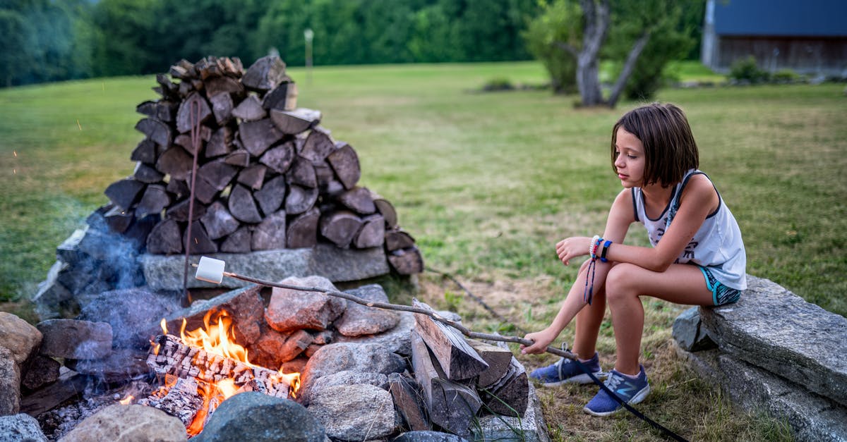 How can a Green Card holder prove their length of absence when exiting and entering through a Mexican land crossing? - Full body of little girl in summer outfit sitting on stone bench and roasting marshmallow on twig on fire near boulders and logs on grassy field near trees in summer evening