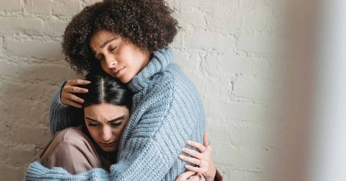 How can a traveller to Namibia best support African businesses? [closed] - Sad African American woman with closed eyes hugging and consoling depressed female friend near white wall in light room at home