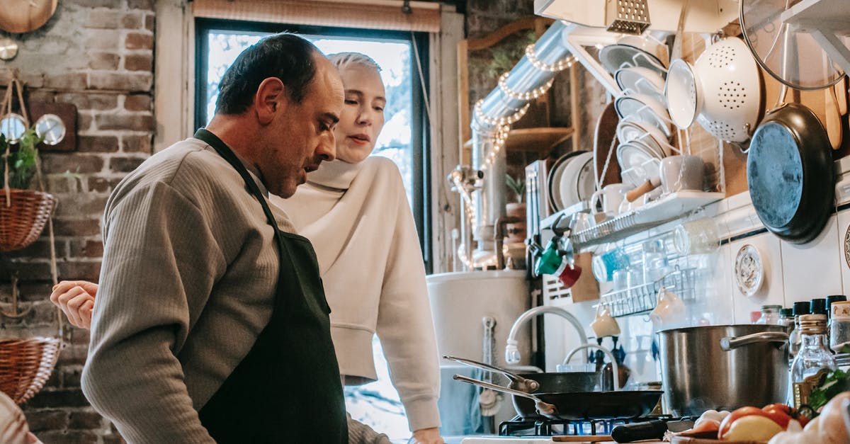 How can husband get his Schengen visa processed when he is at sea? [closed] - Concentrated middle aged ethnic man in apron and woman standing together in kitchen during dinner preparation at home