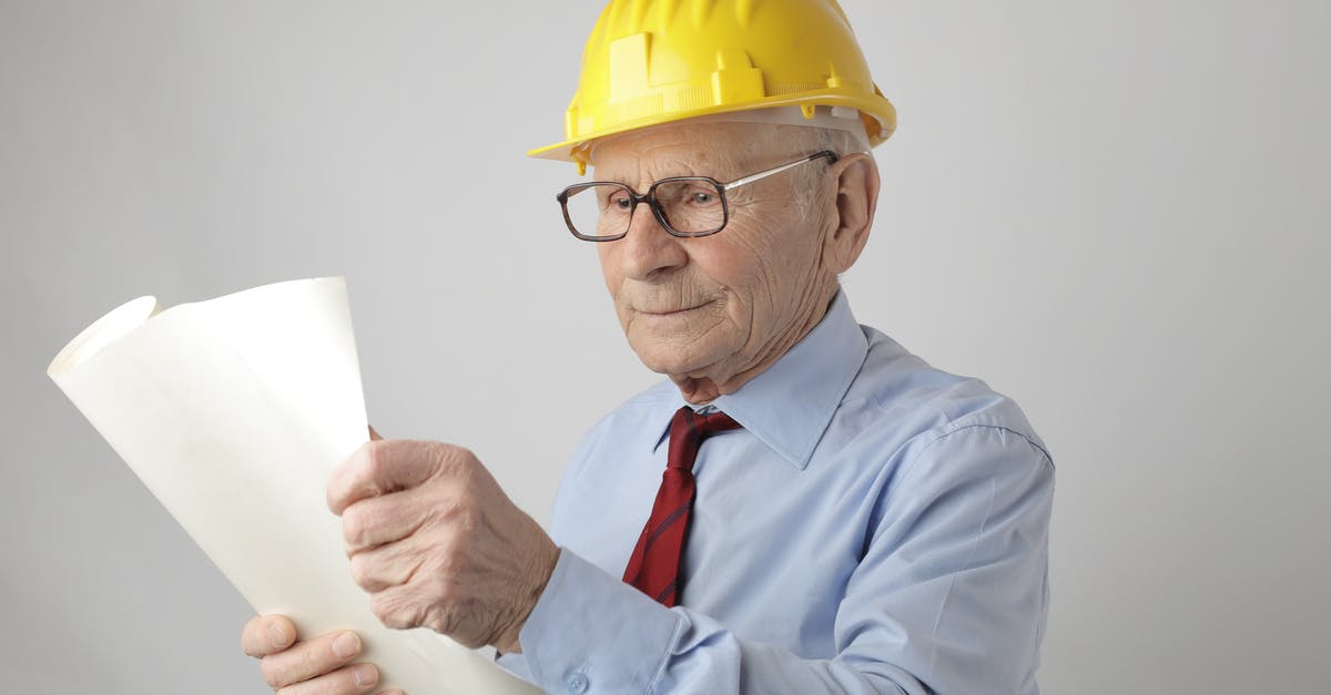 How can I determine if it is possible to check luggage during a layover? - Senior male engineer reading blueprint in studio