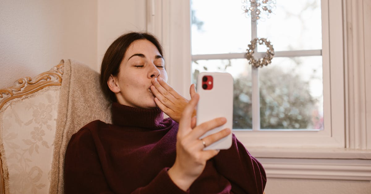 How can I most affordably use my iPhone in the UK during a long-term study abroad period? [closed] - Woman Sitting on Chair while Having a Video Call
