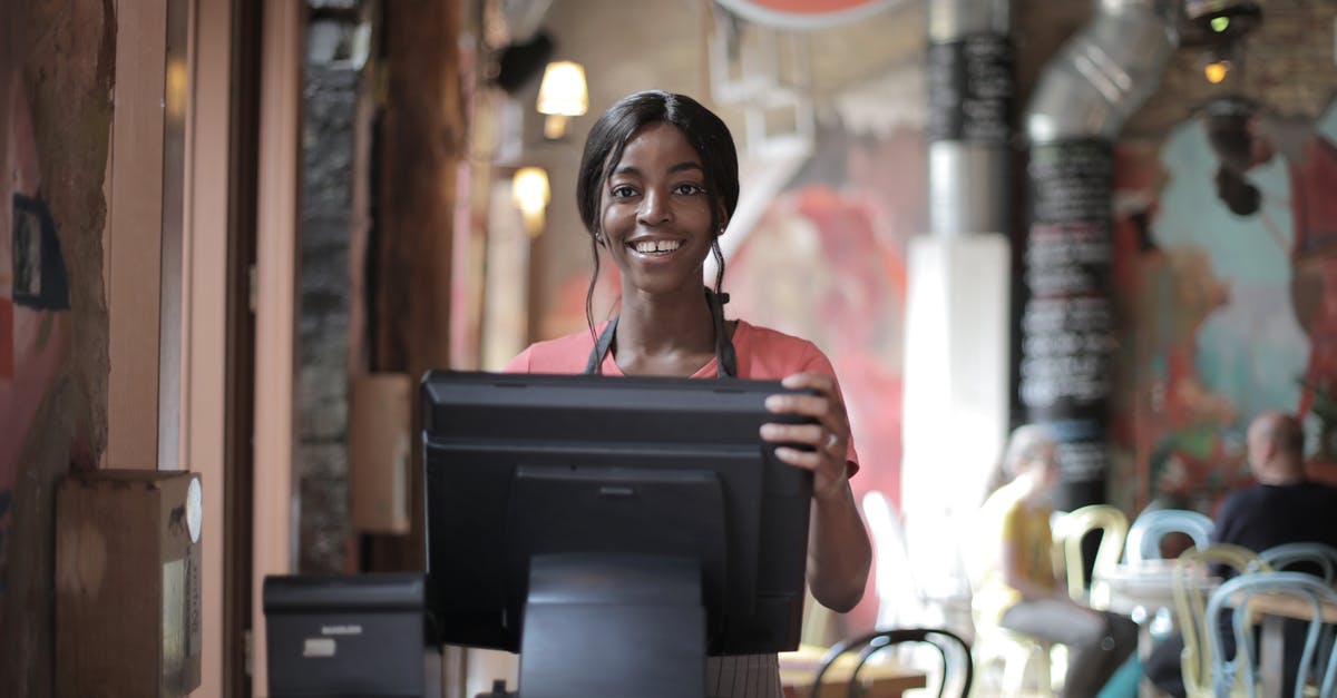 How can I reach Alitalia customer service? - Positive young woman in uniform smiling while standing at counter desk in cafe How can I reach Alitalia customer service? - Positive young woman in uniform smiling while standing at counter desk in cafe