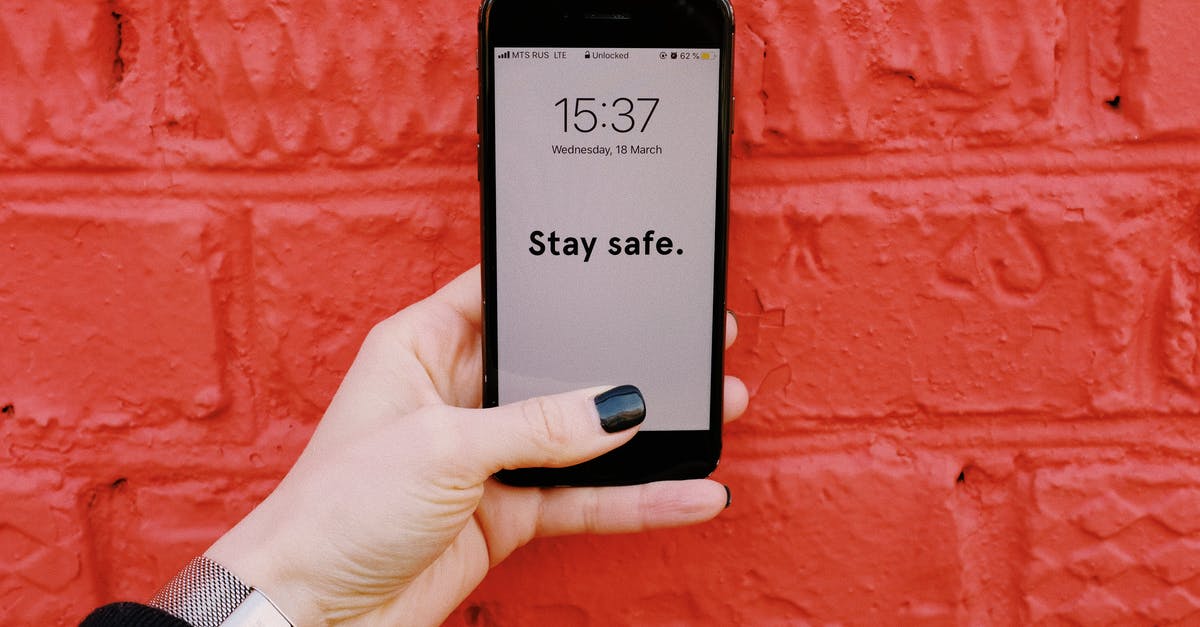 How can I show that I have enough funds to support myself during my stay? - Anonymous crop woman demonstrating smartphone with inscription Stay sage on screen near brick wall painted red