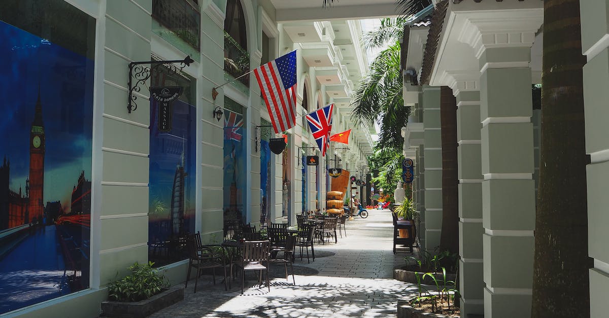 How can I travel between US towns without flying? - Narrow paved street with outdoor cafe and classic styled buildings decorated with various countries flags and banners in sunlight How can I travel between US towns without flying? - Narrow paved street with outdoor cafe and classic styled buildings decorated with various countries flags and banners in sunlight