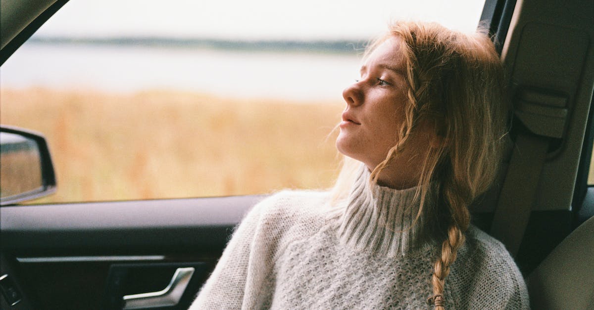 How can non-Caucasians avoid suspicious looks when traveling in the West? - Woman in Sweater Sitting Inside a Car