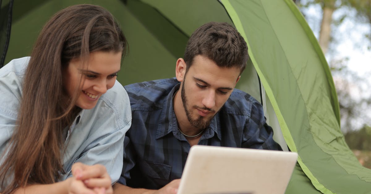 How can you enjoy nature, when it looks better in photographs than in person? [closed] - Happy couple resting in tent and surfing laptop while spending time together in park
