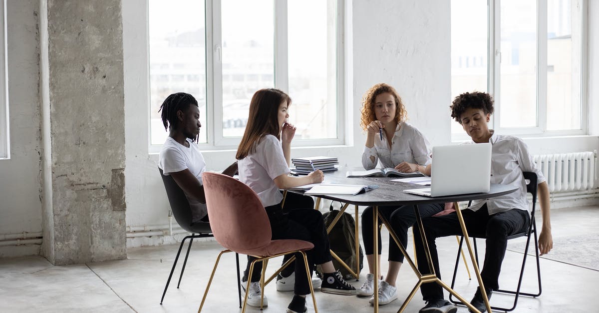 How did the Raffles staff know my colleague had been unwell during the week? - Full length concentrated multiethnic coworkers in formal wear working on project together and gathering at desk in light loft workplace
