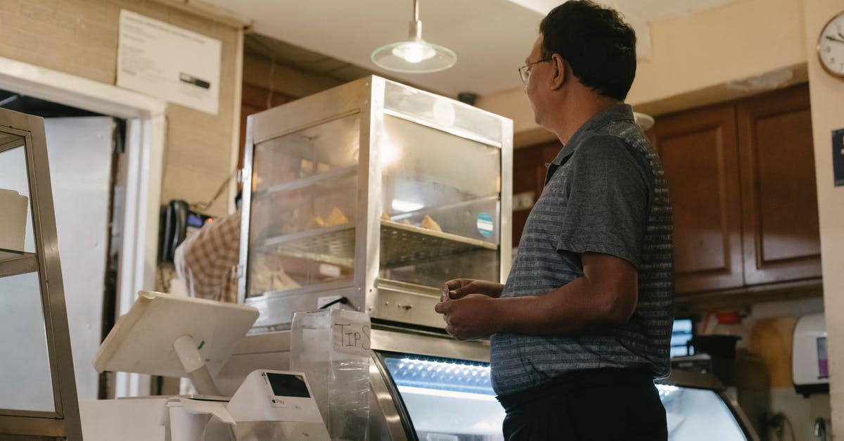 How do airports check incoming goods [closed] - Side view of ethnic male wearing casual clothes standing near showcase and cash register while buying food in grocery store