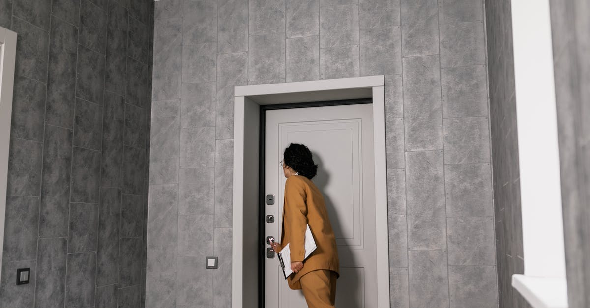 How do door locks work in South America? - Woman in Brown Coat and Brown Pants Standing in Front of Door
