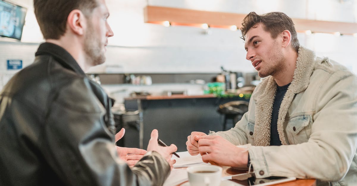 How do I explain employment contract changes in my UK visa application? - Side view of crop young man talking about business project at table with papers and looking at partner on blurred background How do I explain employment contract changes in my UK visa application? - Side view of crop young man talking about business project at table with papers and looking at partner on blurred background