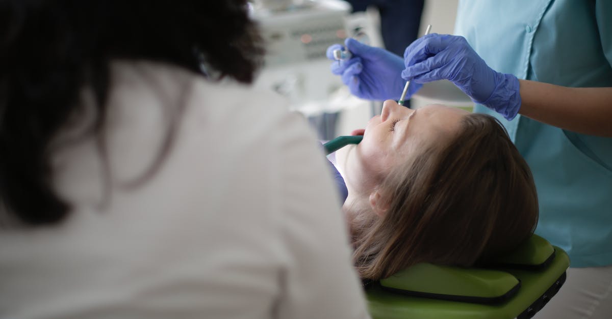 How do I mention a previous US visit using an OCI card? [closed] - Faceless female dentist using drill and mouth mirror while curing teeth of patient
