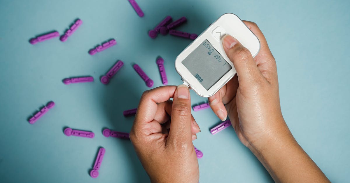 How do I prevent damage to electronic devices at airport security? - Top view of crop anonymous female diabetic measuring blood sugar with glucometer over scattered lancets