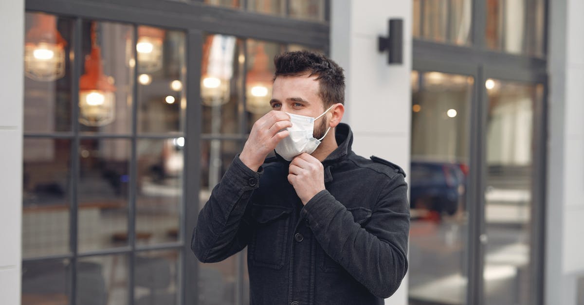How do I prevent painful air pressure differences in my ear when flying? [duplicate] - Young man in medical mask on urban street during Coronavirus pandemic