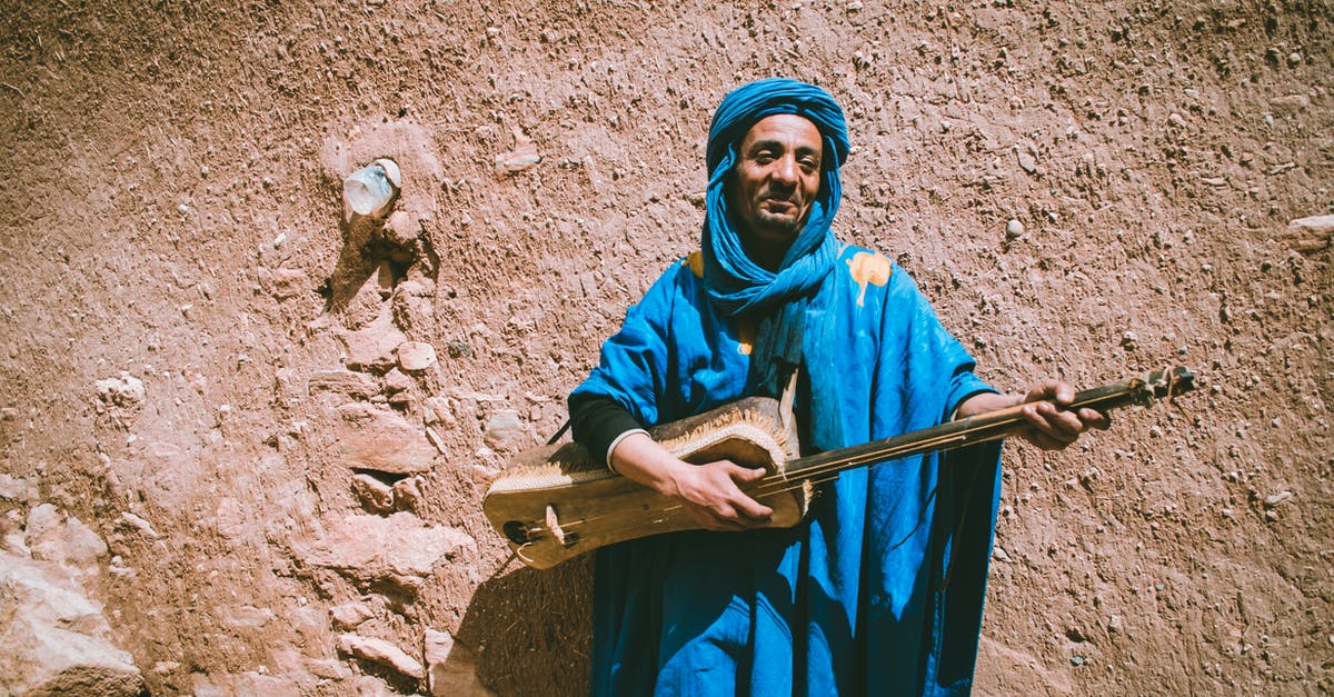 How do I travel with musical instruments? - Man in Brown Jacket and Brown Hat Standing on Sidewalk With A Guitar How do I travel with musical instruments? - Man in Brown Jacket and Brown Hat Standing on Sidewalk With A Guitar