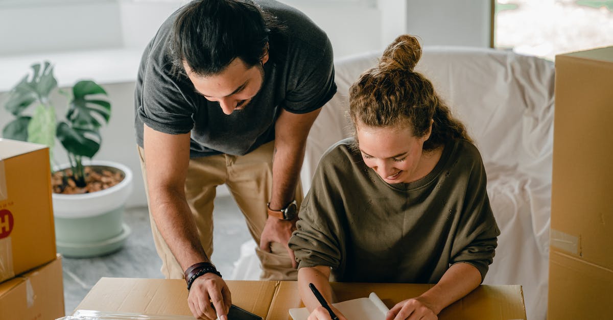 How do you pack your dirty clothing when moving from hotel to hotel? - Cheerful diverse couple writing in notebook near boxes before relocation How do you pack your dirty clothing when moving from hotel to hotel? - Cheerful diverse couple writing in notebook near boxes before relocation