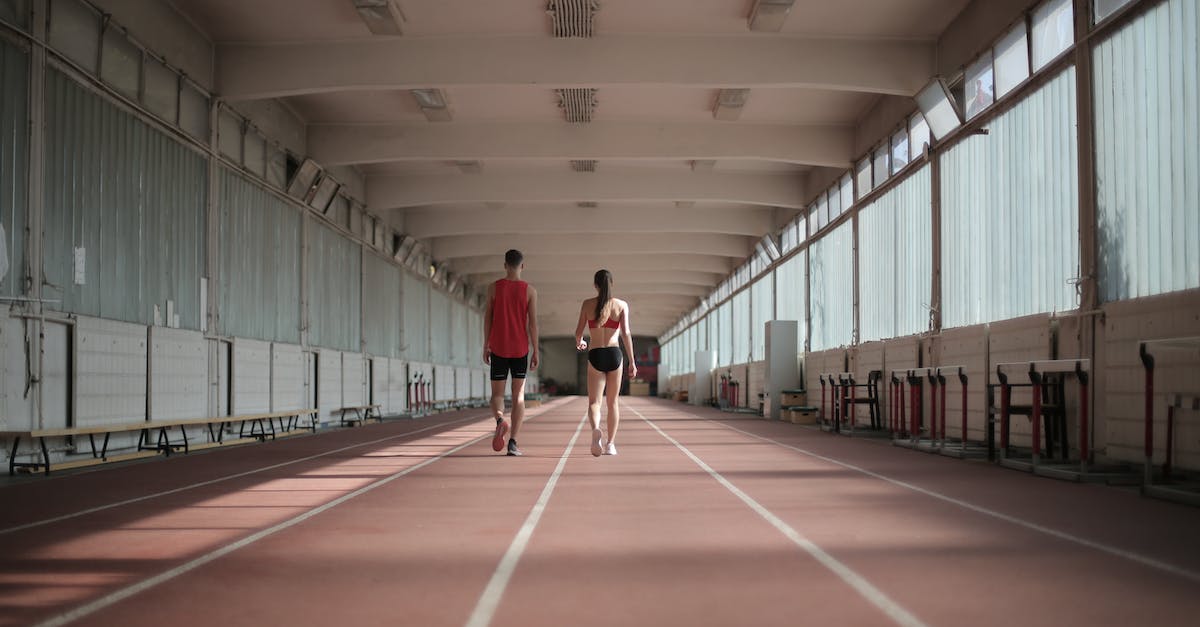 How do you prepare for long haul flights? - Back view of sportsman and sportswoman in activewear walking along running track in athletics arena during warming up before training How do you prepare for long haul flights? - Back view of sportsman and sportswoman in activewear walking along running track in athletics arena during warming up before training