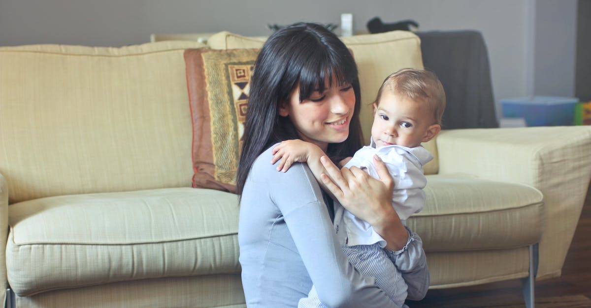 How do you seat a baby securely on a coach transfer? - Woman in Gray Sweater Carrying Toddler in White Button-up Shirt How do you seat a baby securely on a coach transfer? - Woman in Gray Sweater Carrying Toddler in White Button-up Shirt