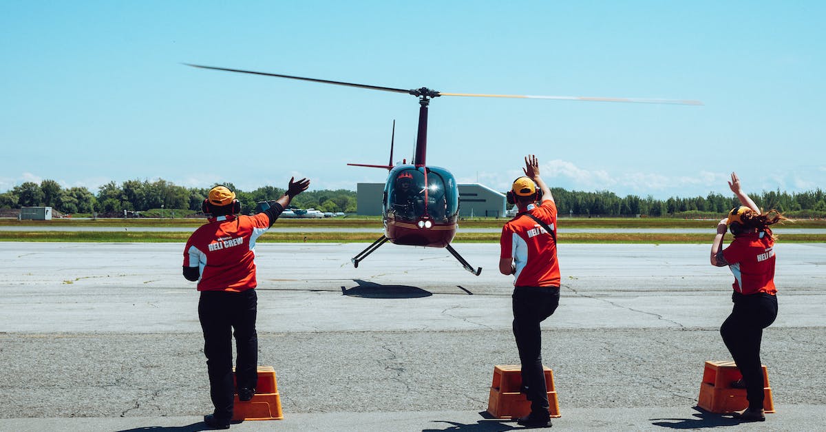 How does VIP service work at the Managua Airport? - Back view of anonymous ground crews in uniforms and headsets meeting passenger helicopter on airfield after flight against cloudless blue sky How does VIP service work at the Managua Airport? - Back view of anonymous ground crews in uniforms and headsets meeting passenger helicopter on airfield after flight against cloudless blue sky