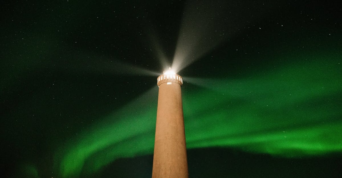 How far away from artificial light do you need to get to experience the night sky without light polution? - From below of high lighthouse tower burning in dark night against black sky with glowing green aurora light in north How far away from artificial light do you need to get to experience the night sky without light polution? - From below of high lighthouse tower burning in dark night against black sky with glowing green aurora light in north