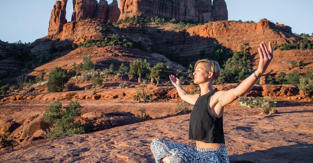 How fit does one need to be for the Grand Canyon rim-to-rim - Young slim lady in summer top and hippie pants sitting with arms spread and eyes closed on rough ground while doing yoga near magnificent sunlit canyons