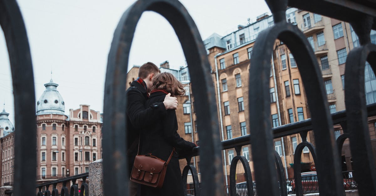 How I change the date for my Australian transit visa? [closed] - From below of anonymous female and male in warm clothes standing near railing together and hugging in cold weather