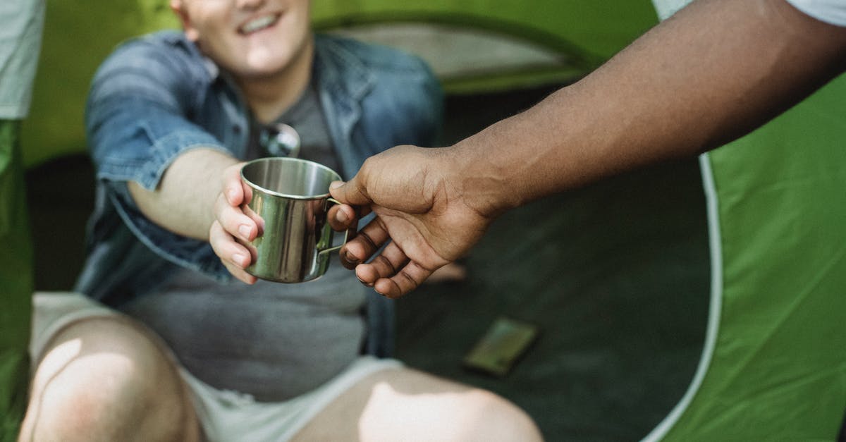 How long would it take to hike from Hamar to Lillehammer? - Crop anonymous African American man taking camping metal cup from cheerful friend sitting in tent in daytime How long would it take to hike from Hamar to Lillehammer? - Crop anonymous African American man taking camping metal cup from cheerful friend sitting in tent in daytime