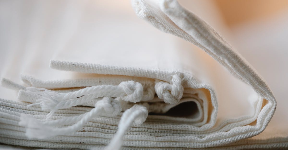 How many bags can I check in as part of the included luggage allowance on Thomson Airways? [closed] - Pile of folded white cotton bags with ropes made of ecological cloth placed on table in light room on blurred background
