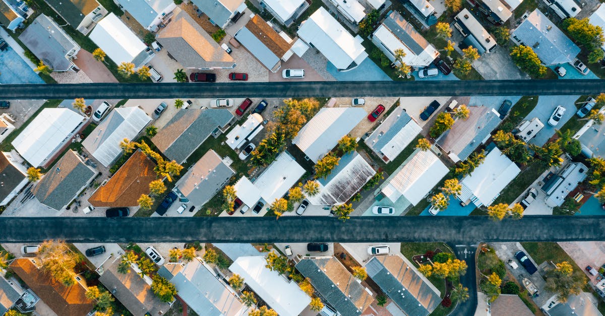 How many passengers allowed in a car in Oklahoma, USA? - Aerial view of many similar roofs of residential buildings with growing trees and parked cars near narrow asphalt roads in contemporary town in daylight