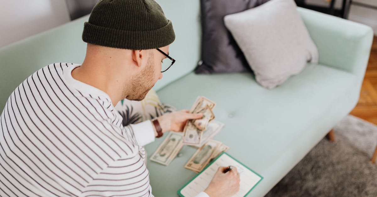 How much cash do I need when entering Germany? - Man Writing on a Notebook While Holding His Money How much cash do I need when entering Germany? - Man Writing on a Notebook While Holding His Money