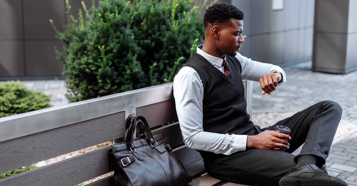 How much time is needed for check-in at Zurich? - Man in Black Vest Checking the Time on His Wristwatch while Sitting on a Wooden Bench How much time is needed for check-in at Zurich? - Man in Black Vest Checking the Time on His Wristwatch while Sitting on a Wooden Bench