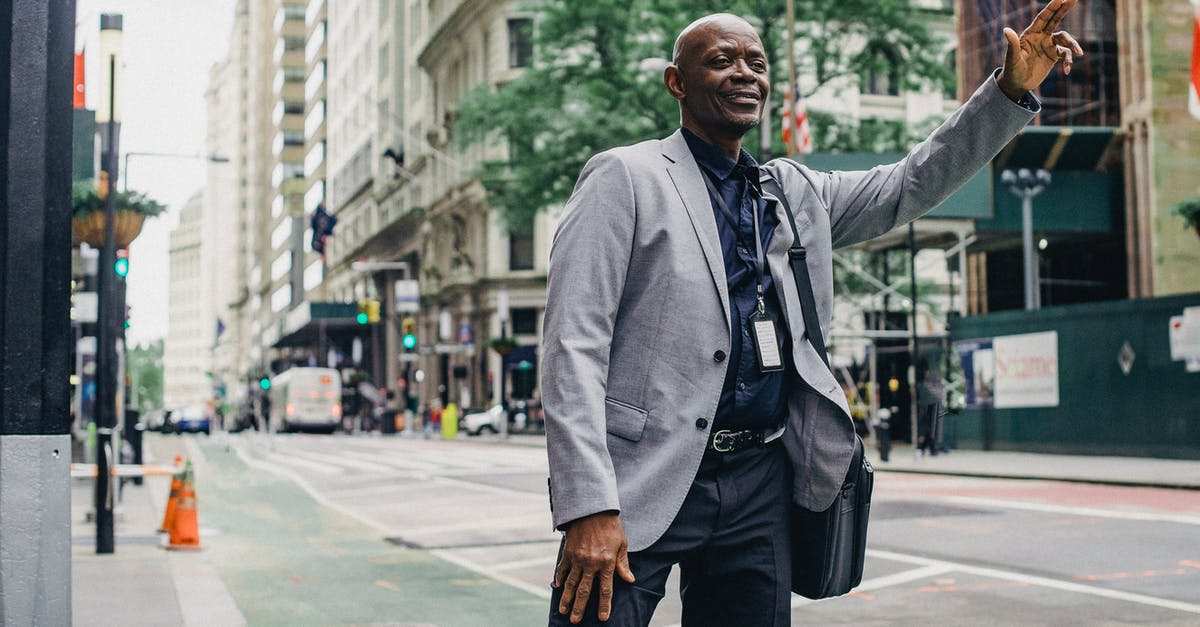 How reliable is public transport in Colombia? - Cheerful successful African American entrepreneur waiting for taxi on local street of modern city How reliable is public transport in Colombia? - Cheerful successful African American entrepreneur waiting for taxi on local street of modern city