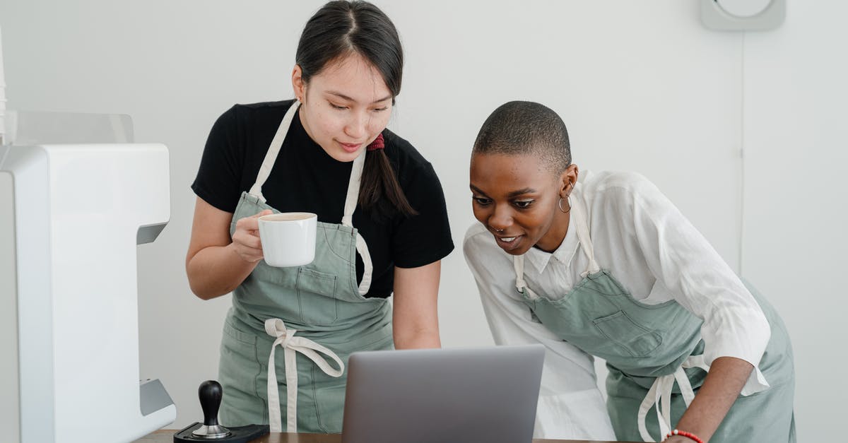 How should I explain a previous refusal in a new UK visa application? - Young Asian coffee house worker explaining to new African American coworker how to use special computer program during break at work