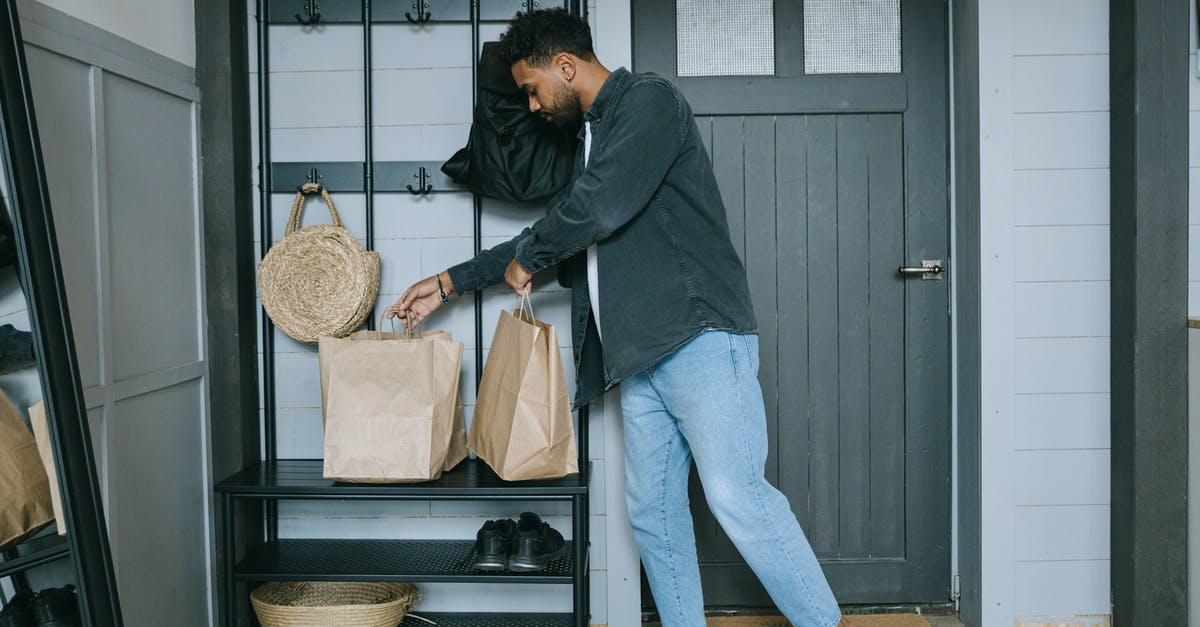 How should one prepare for a business trip to Manila? - Man in Black Long Sleeve Shirt and Blue Denim Jeans Standing Beside Black Wooden Door How should one prepare for a business trip to Manila? - Man in Black Long Sleeve Shirt and Blue Denim Jeans Standing Beside Black Wooden Door