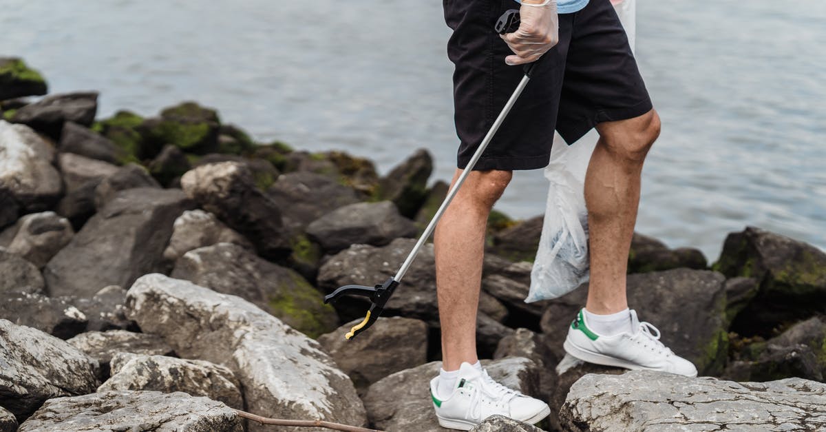How strict are the airlines if one's bag is only 2cm bigger than the rule? [closed] - Man in Blue Shorts and White Nike Sneakers Standing on Rocky Shore