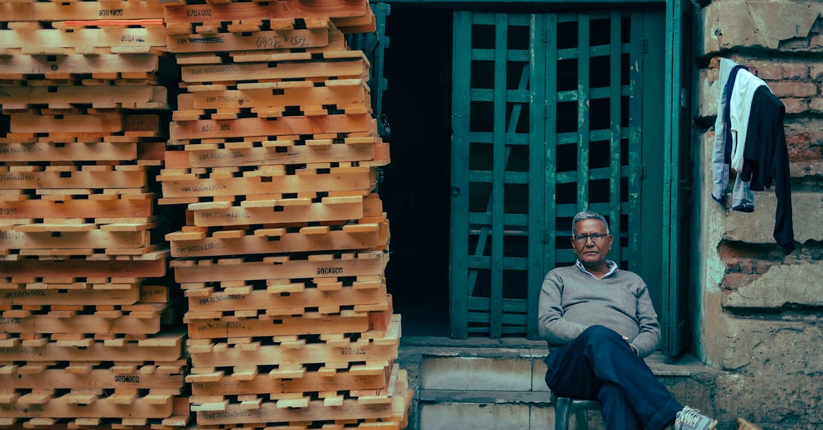 How to find a decent taxi company in Chicago? - Man Sitting in Front of a Building with a Stack of Pallets Next to Him How to find a decent taxi company in Chicago? - Man Sitting in Front of a Building with a Stack of Pallets Next to Him