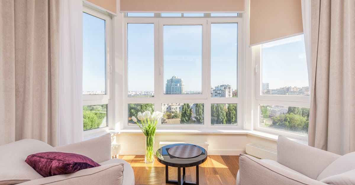 How to find neighboring apartments/self-catering accommodation? - Interior of modern penthouse with comfortable white armchairs and round side table placed near windows overlooking city in sunny day How to find neighboring apartments/self-catering accommodation? - Interior of modern penthouse with comfortable white armchairs and round side table placed near windows overlooking city in sunny day