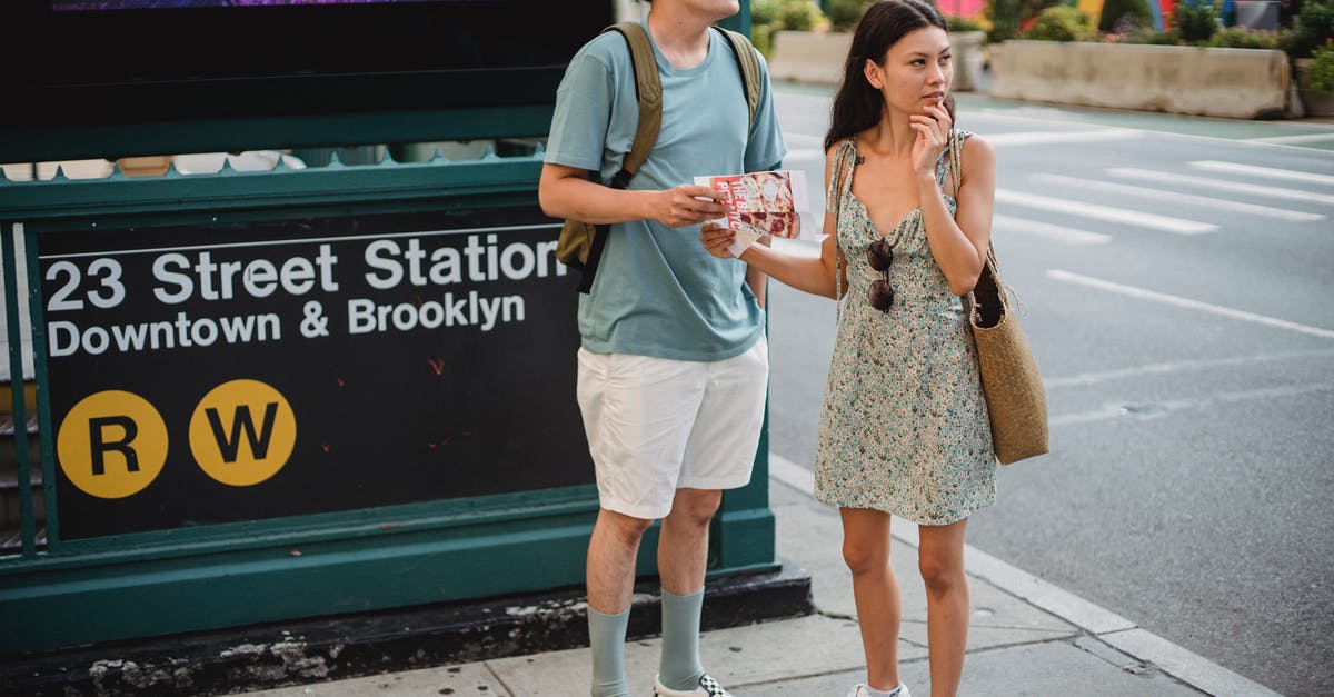 How to find the Flixbus timetable for a specific route? - Full body of diverse couple standing with map while trying to find direction in city center during trip How to find the Flixbus timetable for a specific route? - Full body of diverse couple standing with map while trying to find direction in city center during trip