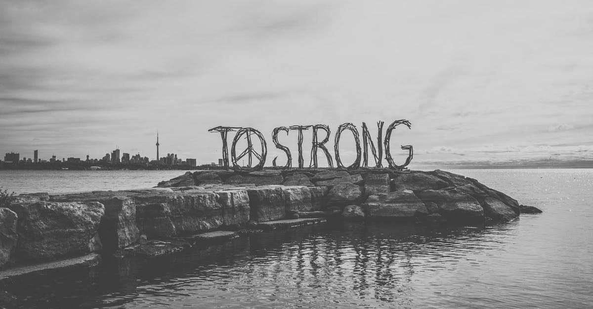How to get a letter of invitation to travel to Canada? [closed] - Black and white big inscription To strong with Peace symbol located on stone pier against calm sea and Toronto cityscape