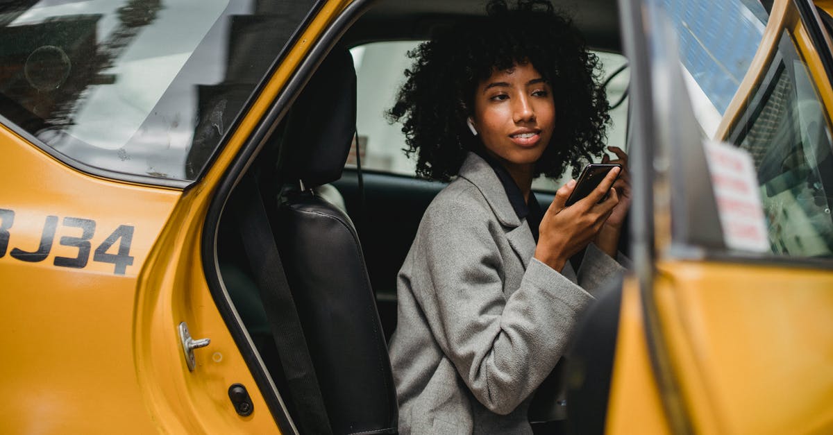 How to get a taxi on Prague streets? - Black woman getting out of taxi on street How to get a taxi on Prague streets? - Black woman getting out of taxi on street