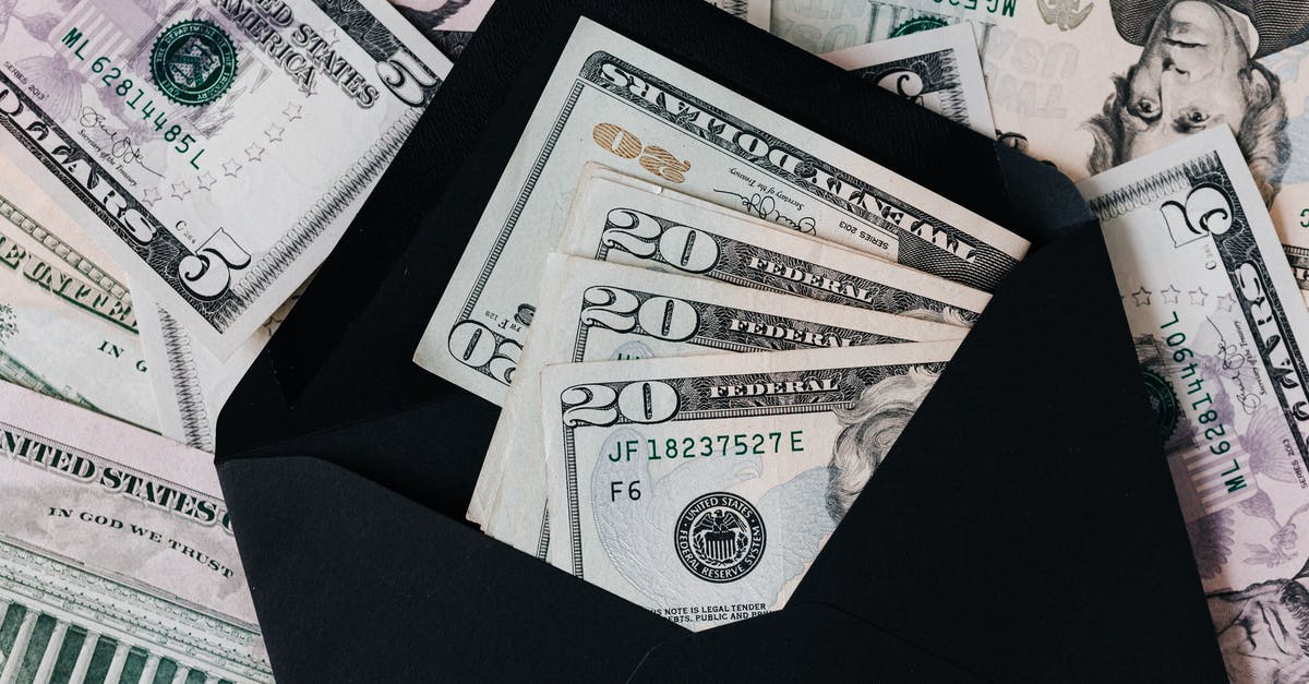 How to get apostille at the U.S. State Department for FBI background check? - From above of dollar bills in opened black envelope placed on stack of United states cash money as concept of personal income
