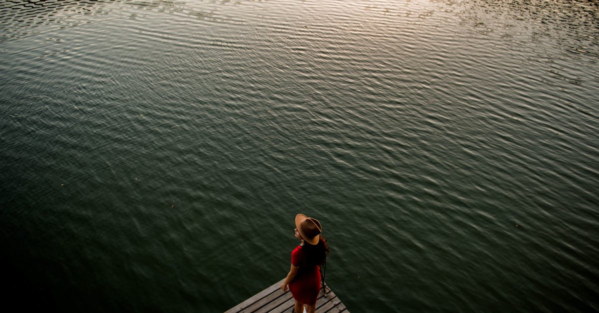 How to get back to Sathorn pier from Yaowarat? - From above of anonymous female traveler in stylish dress and hat standing on wooden pier against rippling lake and admiring nature at sunset