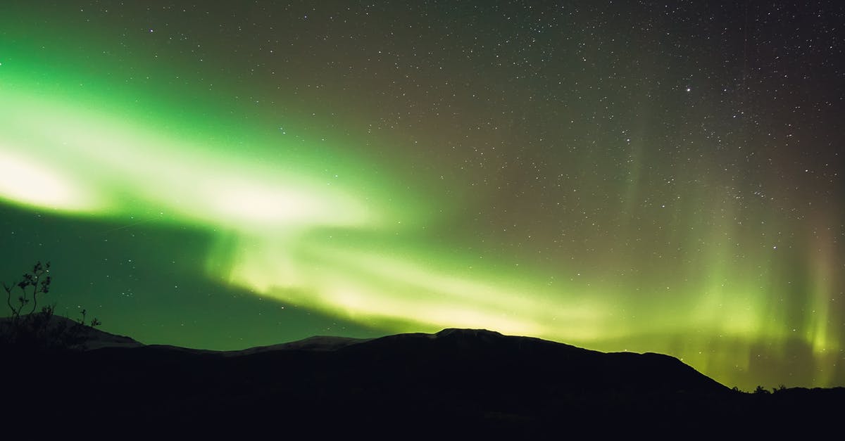 How to get from Caracas to Mount Roraima? - Low angle scenery view of bright green northern lights illuminating mountain silhouette and starry sky in evening