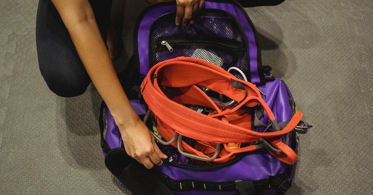 How to get from Flores to Sulawesi? - Crop woman getting safety equipment from violet bag How to get from Flores to Sulawesi? - Crop woman getting safety equipment from violet bag