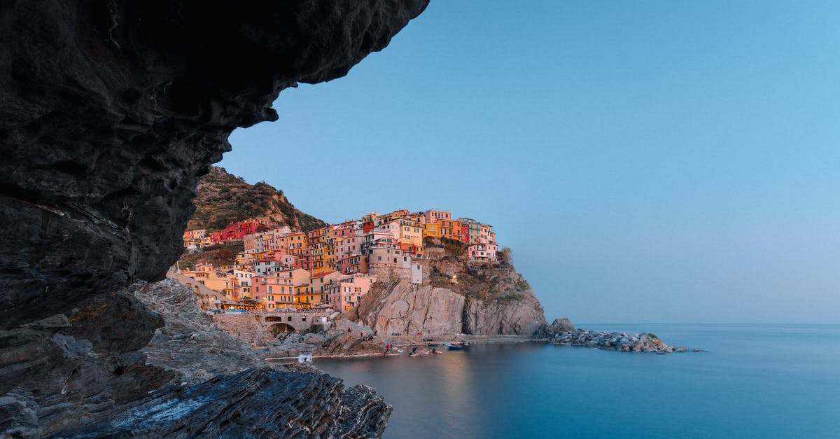 How to get from Genoa to Cinque Terre? - View on magnificent coastal town with colorful buildings from sea cave How to get from Genoa to Cinque Terre? - View on magnificent coastal town with colorful buildings from sea cave