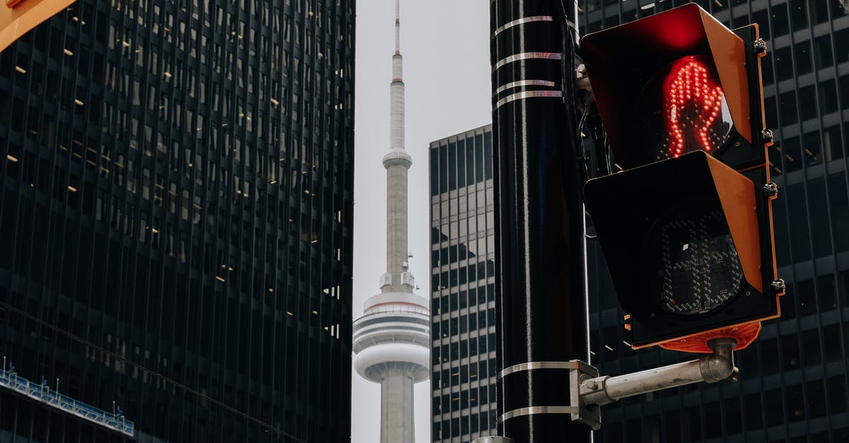 How to get from Toronto Downtown to Pearson Airport - Traffic light with red color and TV tower between skyscrapers How to get from Toronto Downtown to Pearson Airport - Traffic light with red color and TV tower between skyscrapers
